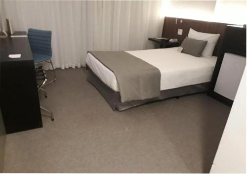 a bedroom with a bed and a desk and a chair at Wyndham Garden Ribeirão Preto Convention in Ribeirão Preto