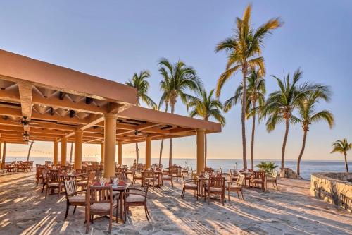 a restaurant on the beach with palm trees and the ocean at Grand Fiesta Americana Los Cabos All Inclusive Golf & Spa in Cabo San Lucas