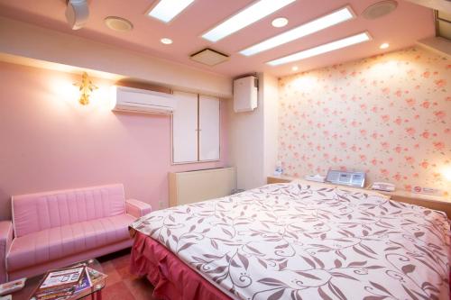 a bedroom with a bed and a pink chair at ファインリゾート in Nagoya