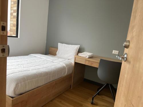 a bedroom with a bed and a desk with a phone at CentralX 21 Bogotá in Bogotá