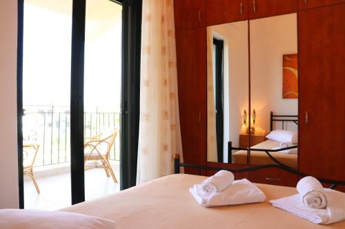 1 dormitorio con toallas en la cama y balcón en Louvis House en Akti Salonikiou