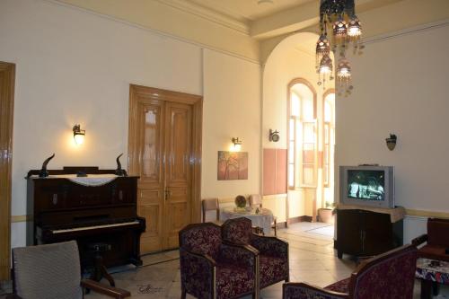 a living room with a piano and a tv at Clement's House Hostel in Alexandria