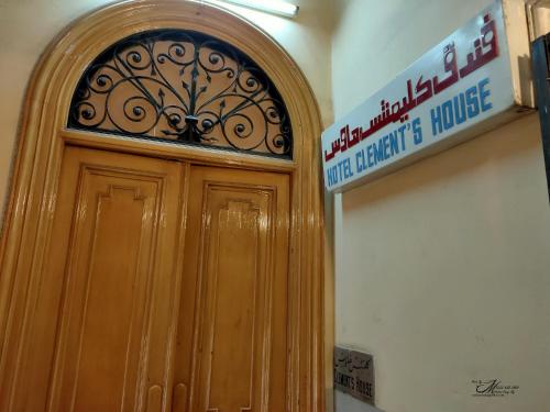 a wooden door in a building with a sign above it at Clement's House Hostel in Alexandria
