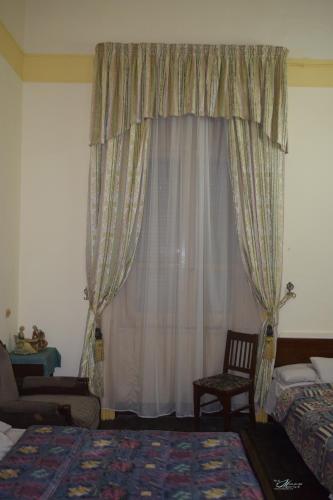 a bedroom with a window with curtains and a chair at Clement's House Hostel in Alexandria