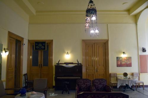 a living room with a piano and a chandelier at Clement's House Hostel in Alexandria