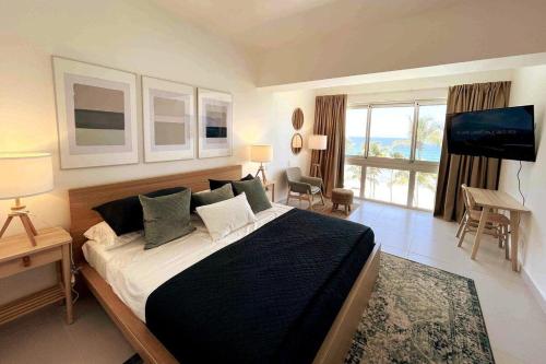 a bedroom with a large bed and a television at Aquarella Beachfront 2BR Sunset Juan Dolio in La Puntica de Juan Dolio