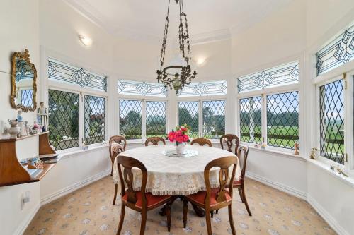 a dining room with a table and chairs and windows at Country Villa Estate in Ngongotaha