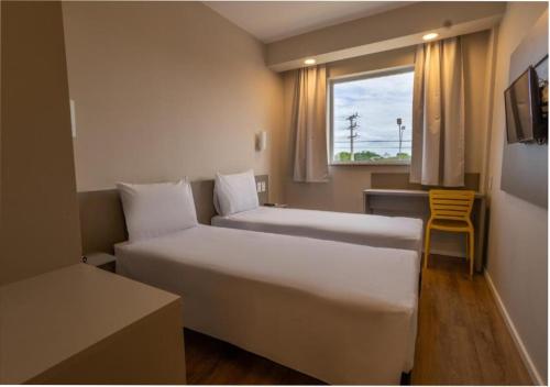 プリマヴェーラ・ド・レステにあるTransamerica FIT Primavera do Lesteのベッド2台と窓が備わるホテルルームです。