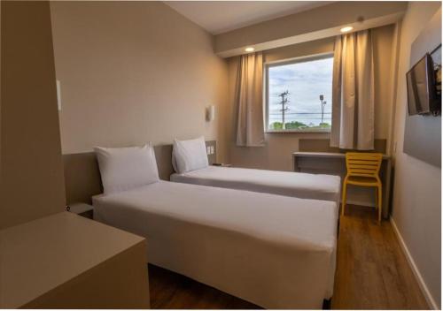 a hotel room with two beds and a window at Transamerica FIT Primavera do Leste in Primavera do Leste