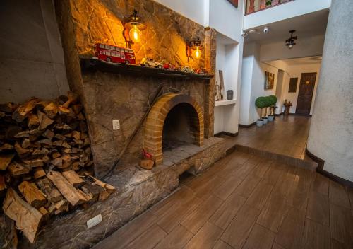 a stone fireplace in a living room with a wooden floor at Vistas del Conde in Heredia