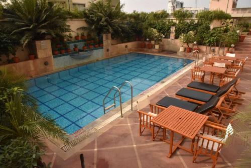 a swimming pool with tables and chairs next to it at Radisson Hotel Varanasi in Varanasi