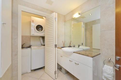a white bathroom with a sink and a mirror at Villa Frangipani in Port Douglas