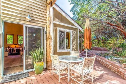 a patio with a table and chairs and an umbrella at CASA de los ARBOLES! Delight & Solitude Abound! in Pine Cove