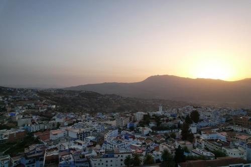 a view of a city at sunset with a mountain in the background at Riad Mauritania in Chefchaouene