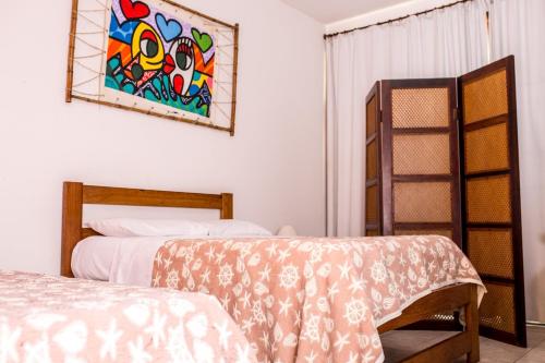 a bedroom with two beds and a painting on the wall at Vila Juquehy Lofts & Suítes in Juquei