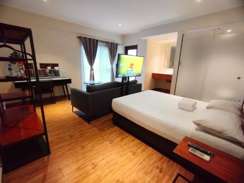 Habitación de hotel con cama, silla y TV en The Hub District Garden Suites en Manila