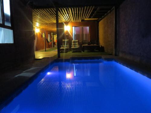 a swimming pool with blue lights in a building at Hostal Kirckir in San Pedro de Atacama
