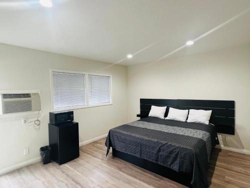 um quarto com uma cama grande e 2 janelas em Holly Park Motel near LAX em Inglewood