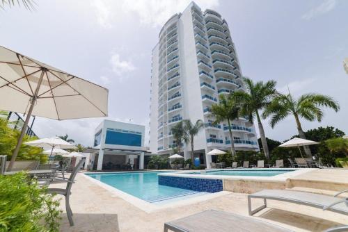 a hotel with a swimming pool and a tall building at Chic and Relax Apartamento Juan Dolio in San Pedro de Macorís
