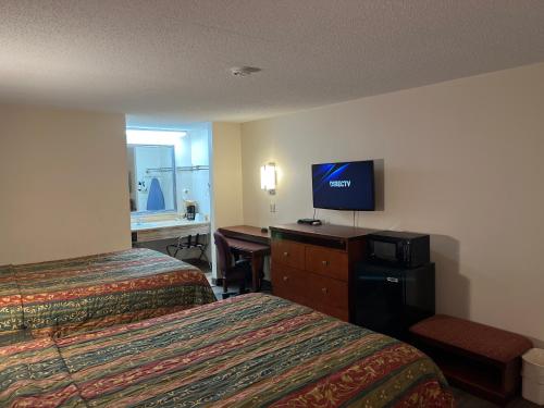 ein Hotelzimmer mit 2 Betten und einem Schreibtisch mit einem TV in der Unterkunft Briarwood Inn in Amory
