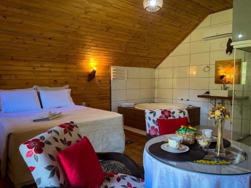 1 dormitorio con cama, mesa y bañera en Pousada Encanto do Avencal en Urubici