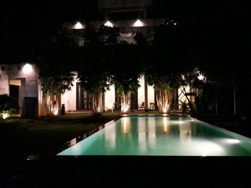 a swimming pool in front of a house at night at KITHULA Boutique Hotel in Hikkaduwa
