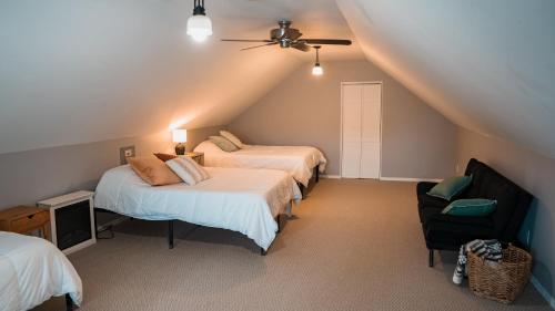 a attic bedroom with two beds and a chair at Sandusky Bay Hot Tub, Gym, Patio, Games, Recreation Watercraft, Waterside Home, check it out! in Port Clinton