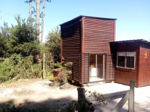 una pequeña cabaña de madera con una valla delante en Casita con vista al mar, en Salinas