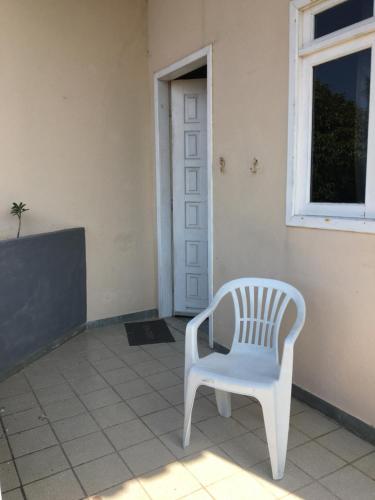 a white chair sitting in front of a door at Suíte aconchegante na praia in Jacaraípe