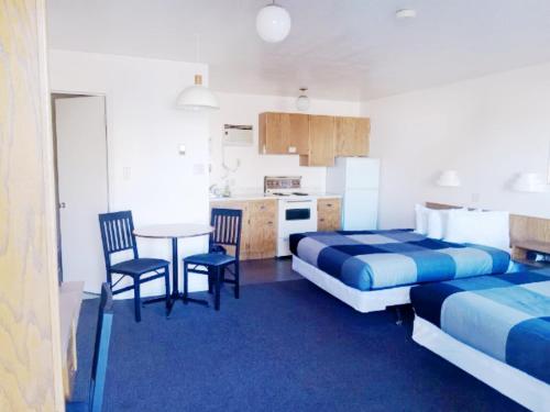 Zimmer mit 2 Betten, einem Tisch und Stühlen in der Unterkunft Cardston Inn in Cardston