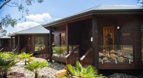 a wooden house with a porch with glass windows at Jamala Wildlife Lodge in Canberra