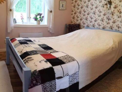 ein Bett mit einer Decke in einem Schlafzimmer in der Unterkunft Holiday home RAMSJÖ III in Ramsjö