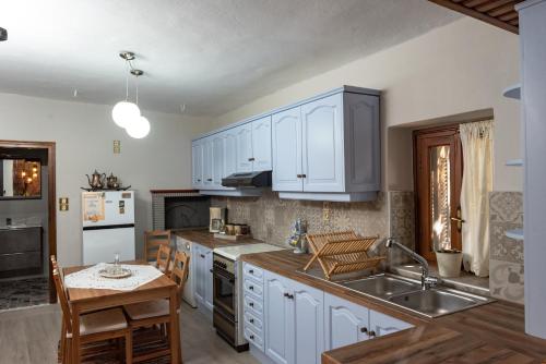 a kitchen with white cabinets and a sink and a table at Μορχέλα, ολόκληρο σπίτι! in Méga Khoríon