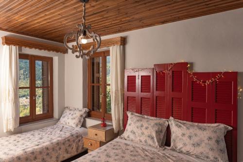 a bedroom with two beds and a red headboard at Μορχέλα, ολόκληρο σπίτι! in Méga Khoríon