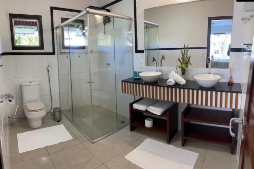 uma casa de banho com um chuveiro, 2 lavatórios e um WC. em Casa Asa Delta - Pipa Natureza em Pipa