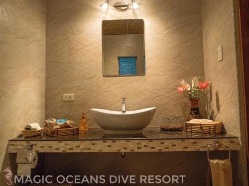 a bathroom with a sink and a mirror at Magic Oceans Dive Resort in Anda