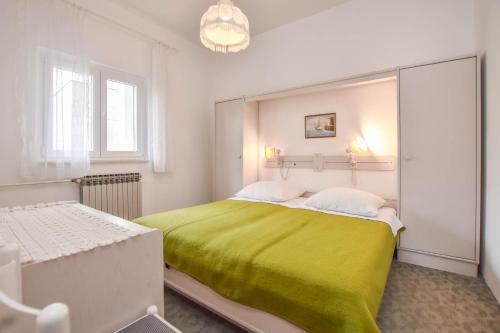 a bedroom with a large bed with a green blanket at Apartments Promina in Biograd na Moru
