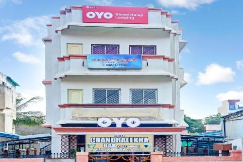 a tall white building with a sign on it at OYO Shree Balaji Lodging in Chikalthān