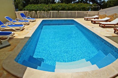a swimming pool with lounge chairs and a swimming pool at Villa Korcula in Prizba