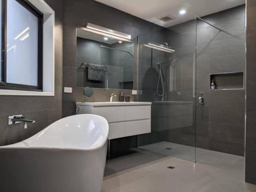uma casa de banho com uma banheira, um lavatório e um chuveiro em Adorable 1 bedroom private apartment em Bright