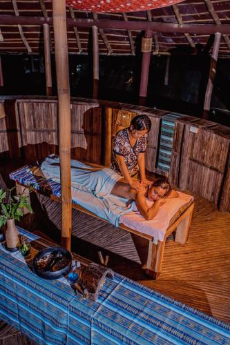 a woman laying on a bed with a woman sitting on it at Atremaru Jungle Retreat in Puerto Princesa City