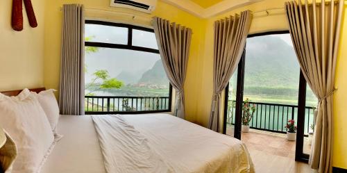 um quarto com uma cama e uma grande janela em Phong Nha Coco Riverside em Phong Nha