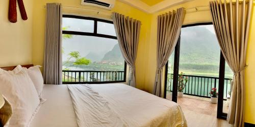 a bedroom with a bed and a large window at Phong Nha Coco Riverside in Phong Nha