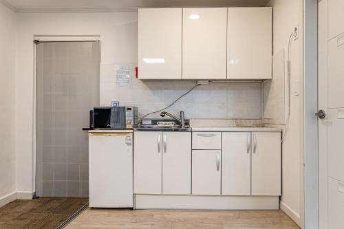 a kitchen with white cabinets and a microwave at Seorak HOT Spring Mammoth Resotel in Sokcho