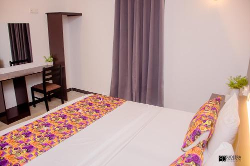 a bedroom with a white bed with a colorful blanket on it at Blooming polhena in Matara
