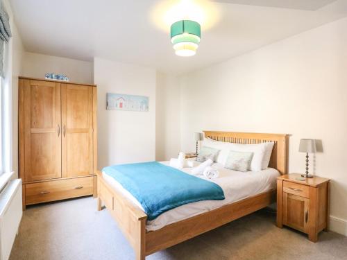 1 dormitorio con 1 cama y armario de madera en South Harbour Cottage en Weymouth