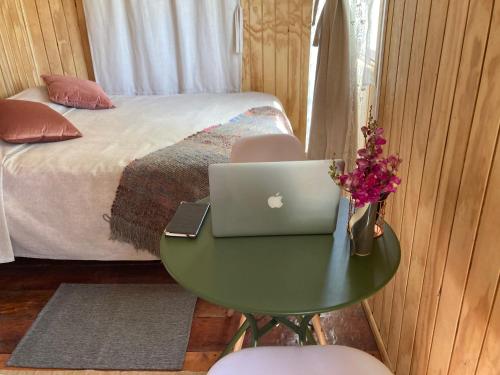 Cabaña Lemupewen Chillán 6 في شيلان: غرفة نوم مع جهاز كمبيوتر محمول على طاولة بجوار سرير