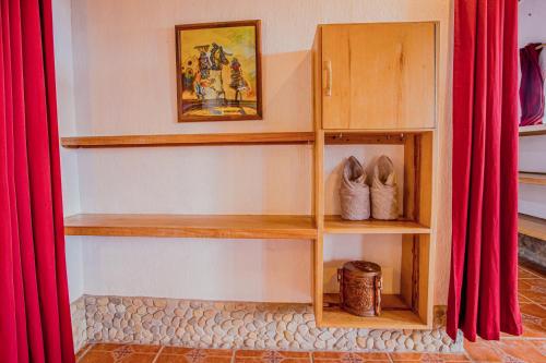 a book shelf with shoes in a room with red curtains at Atremaru Jungle Retreat in Puerto Princesa City
