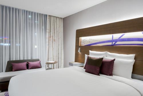 a bedroom with a large white bed with purple pillows at Novotel Ambassador Suwon in Suwon
