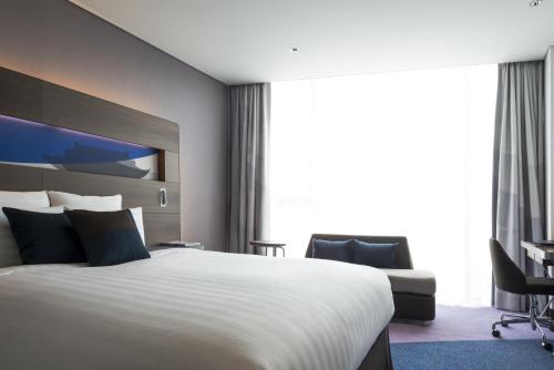 a hotel room with a large bed and a desk at Novotel Ambassador Suwon in Suwon